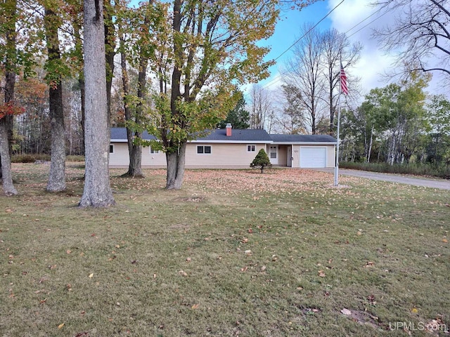 view of front facade featuring an attached garage, a chimney, a front yard, and driveway