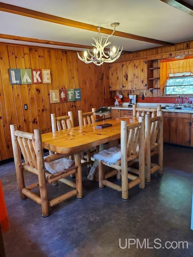 dining area featuring an inviting chandelier, wood walls, and beamed ceiling