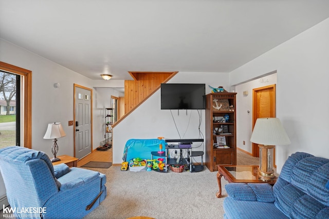 living room with a baseboard radiator, carpet flooring, and stairs
