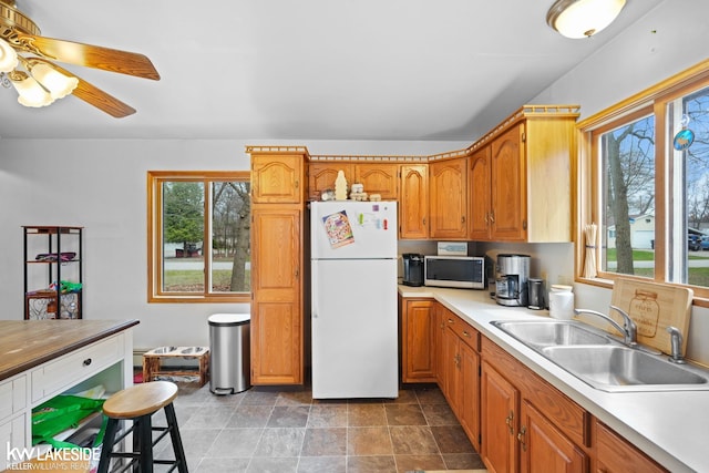 kitchen featuring light countertops, freestanding refrigerator, a sink, and stainless steel microwave
