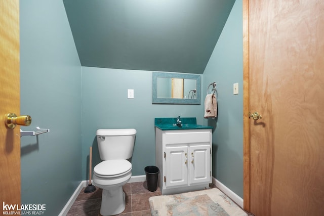 bathroom featuring lofted ceiling, tile patterned flooring, toilet, vanity, and baseboards