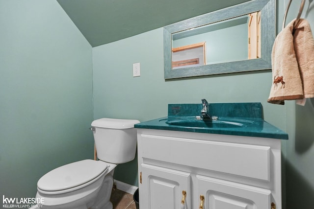 bathroom featuring toilet, vaulted ceiling, baseboards, tile patterned flooring, and vanity