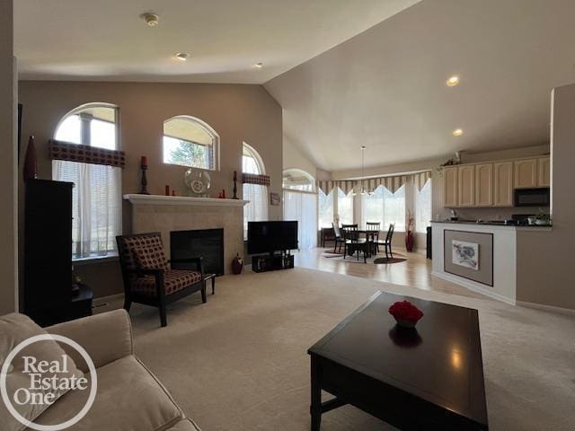 living room with vaulted ceiling, a wealth of natural light, light colored carpet, and a fireplace