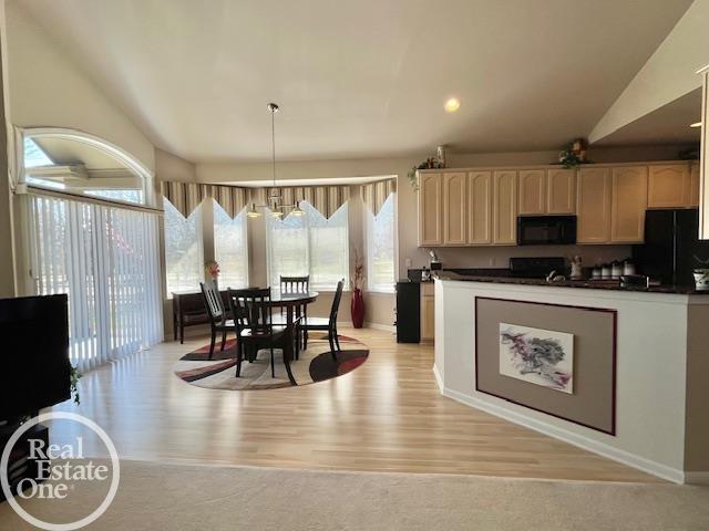 kitchen with dark countertops, baseboards, pendant lighting, black appliances, and light wood-style flooring