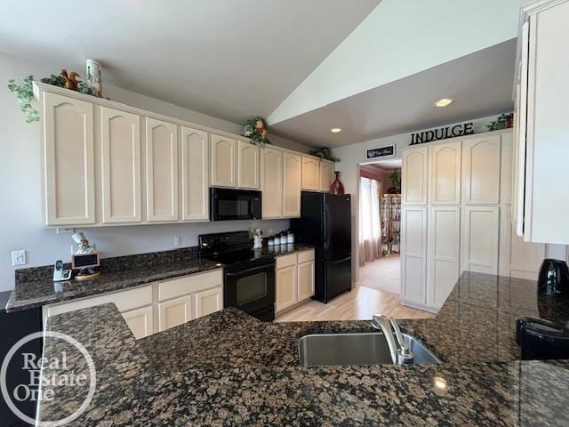 kitchen with a sink, dark stone countertops, white cabinetry, lofted ceiling, and black appliances