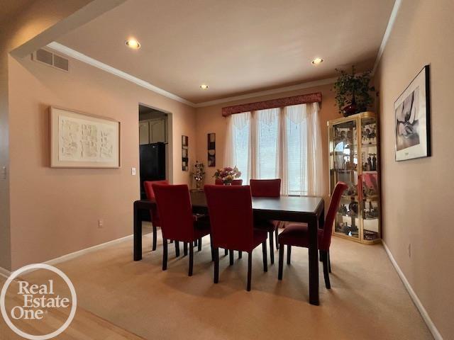 dining area featuring light colored carpet, baseboards, crown molding, and visible vents