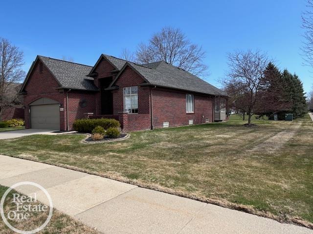 view of property exterior featuring a lawn, driveway, a shingled roof, an attached garage, and brick siding