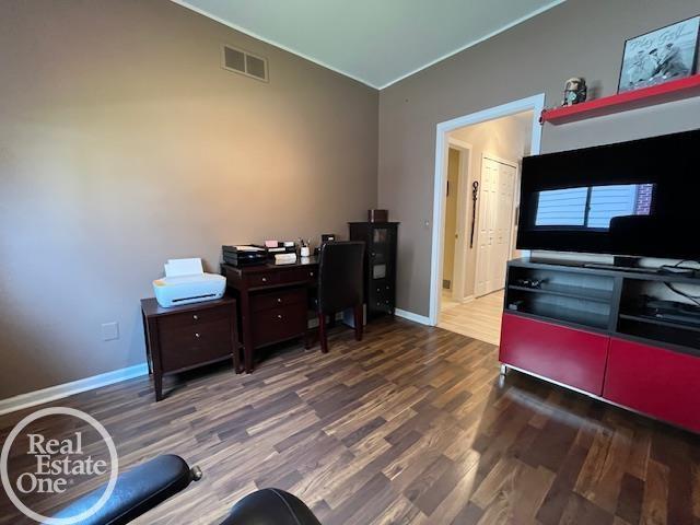 office area featuring vaulted ceiling, baseboards, wood finished floors, and visible vents