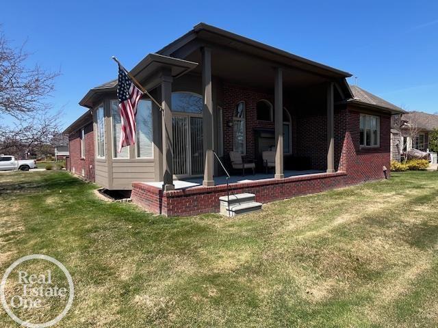view of side of home featuring brick siding, a yard, and a patio