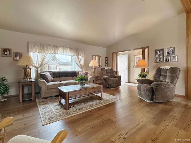 living area with lofted ceiling, baseboards, and wood finished floors