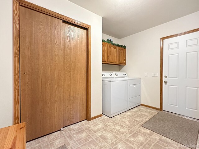 washroom with light floors, washer and dryer, baseboards, and cabinet space