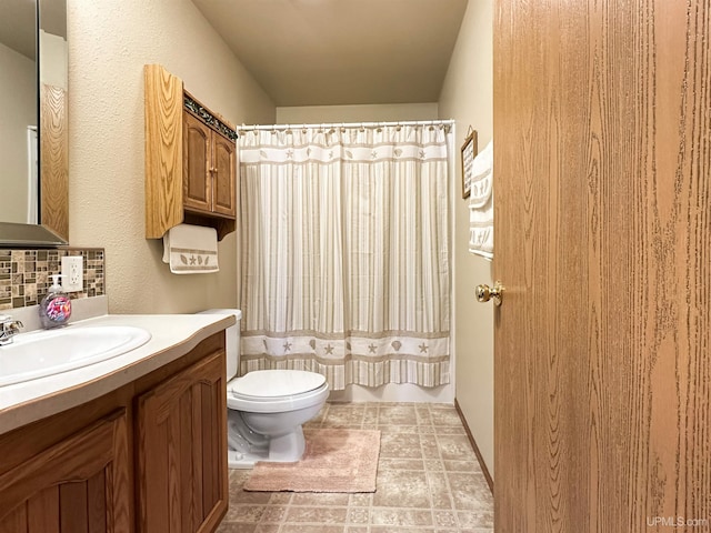 bathroom featuring curtained shower, stone finish floor, toilet, and vanity