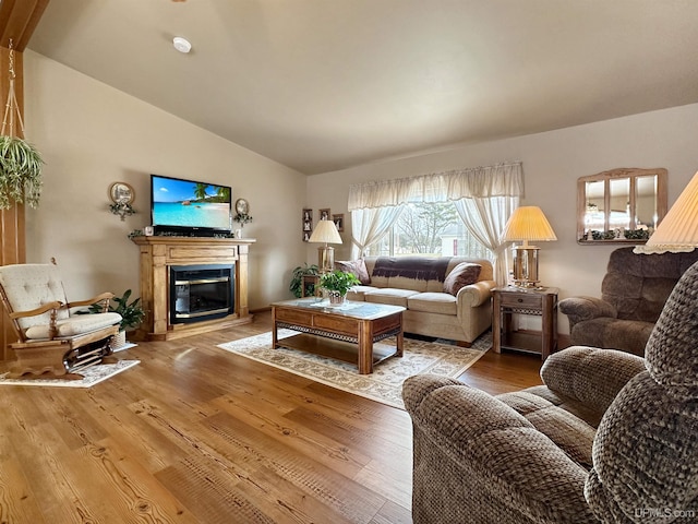 living room with lofted ceiling, a glass covered fireplace, and light wood-style floors