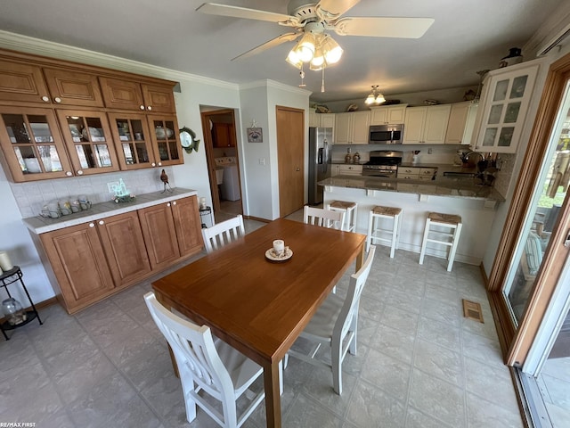 dining space with ceiling fan, washer / clothes dryer, baseboards, ornamental molding, and visible vents