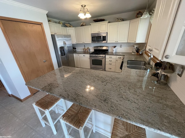 kitchen featuring crown molding, a sink, decorative backsplash, stainless steel appliances, and a peninsula