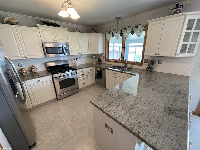 kitchen featuring stainless steel appliances, dark stone countertops, a sink, a peninsula, and white cabinetry