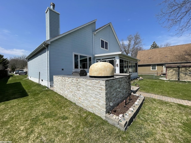 back of house featuring a chimney, area for grilling, a yard, crawl space, and a sunroom