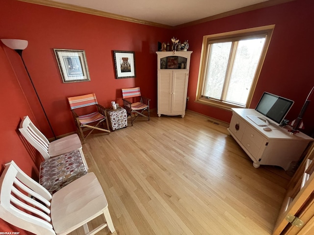 sitting room with light wood-style flooring, baseboards, and crown molding