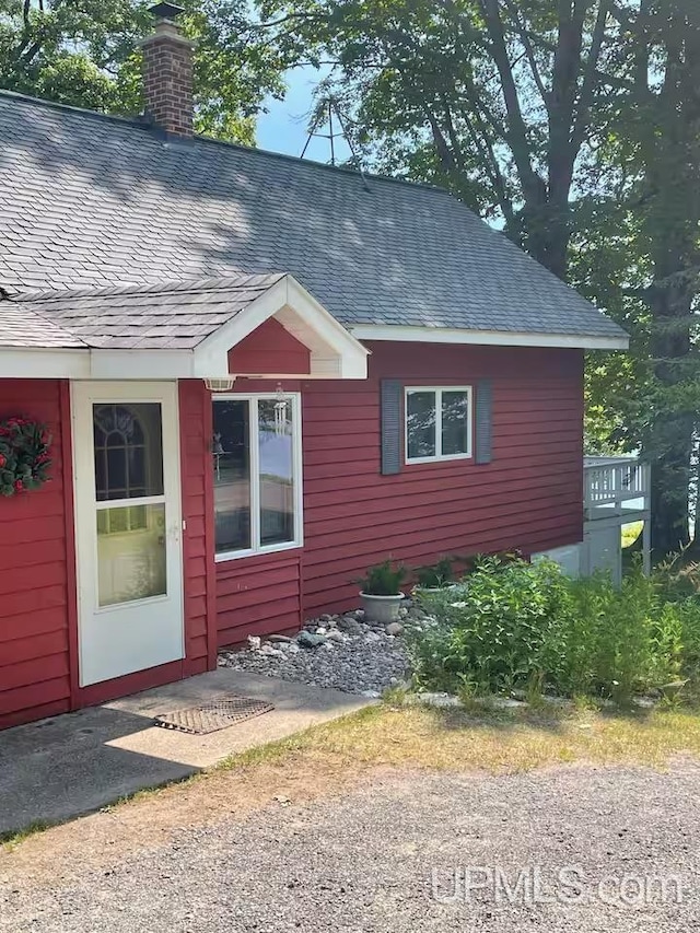 view of side of property featuring a chimney and a shingled roof