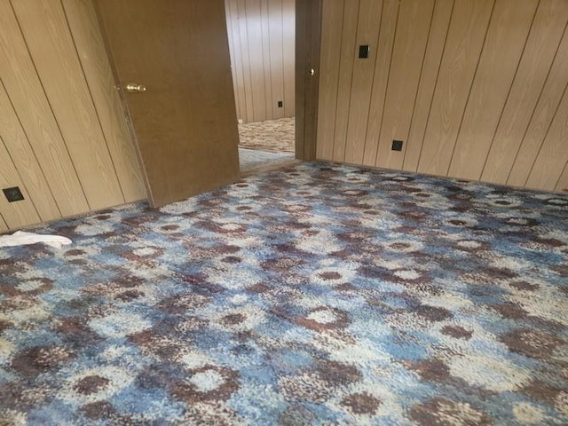 carpeted spare room with wooden walls