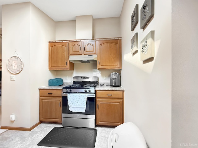 2709 W 6th Ave, Gladstone, MI 49837 - kitchen with baseboards, under cabinet range hood, stainless steel gas range oven, and light countertops