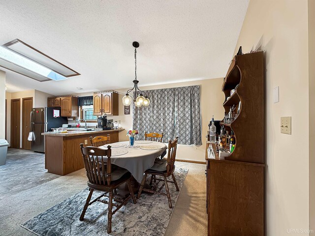 2709 W 6th Ave, Gladstone, MI 49837 - dining room with a skylight, a textured ceiling, a chandelier, and light colored carpet