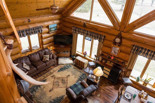 living room with log walls, wood finished floors, and ceiling fan