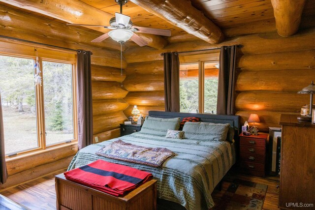 bedroom featuring rustic walls, wood ceiling, and multiple windows