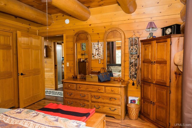 bedroom with wooden walls, wooden ceiling, beamed ceiling, and light wood finished floors
