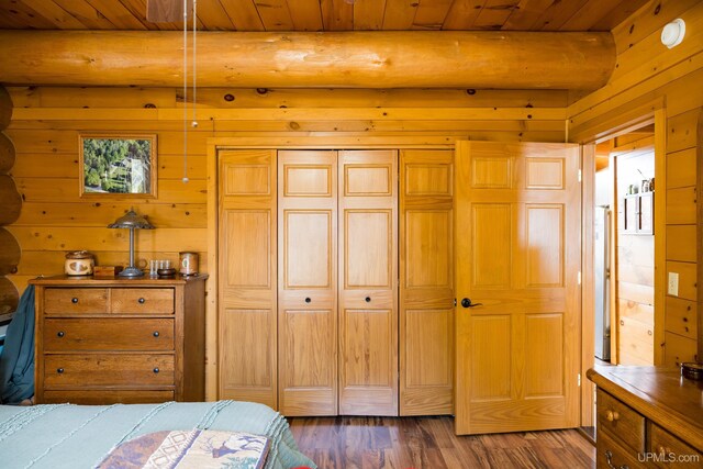bedroom featuring beamed ceiling, wood finished floors, wood walls, a closet, and wooden ceiling