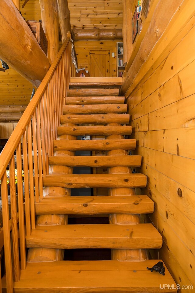 stairs featuring wooden ceiling and log walls