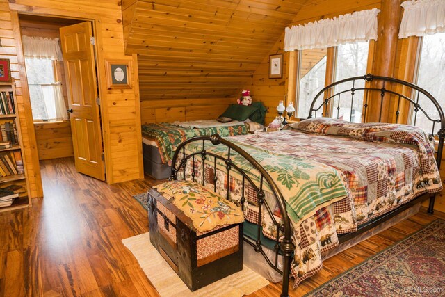 bedroom featuring vaulted ceiling, wood finished floors, and wooden walls