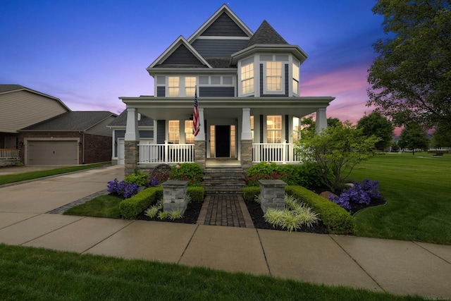 view of front facade featuring a lawn, driveway, a porch, and stone siding