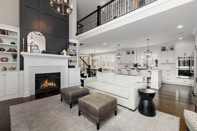 living room with dark wood finished floors, an inviting chandelier, and a fireplace
