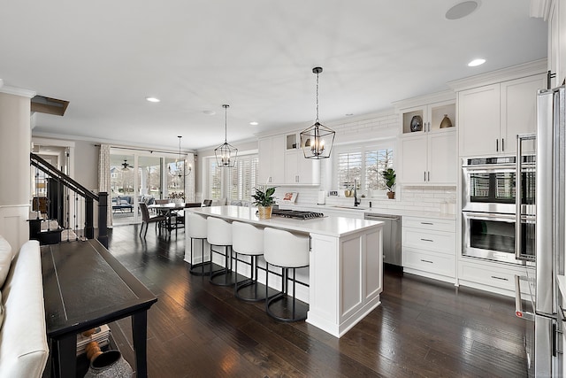 kitchen with glass insert cabinets, light countertops, a breakfast bar area, and appliances with stainless steel finishes