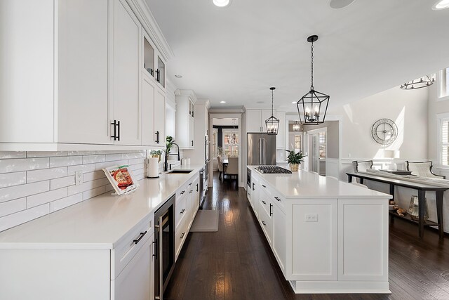 kitchen with a healthy amount of sunlight, beverage cooler, appliances with stainless steel finishes, and a kitchen island