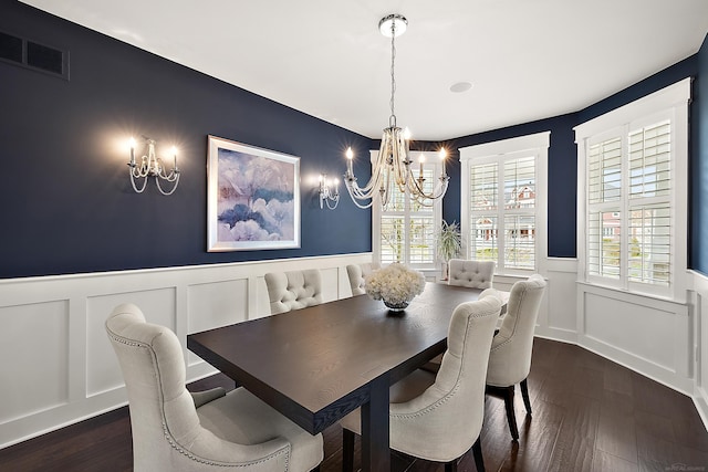 dining area featuring an inviting chandelier, dark wood-style flooring, a wainscoted wall, and a decorative wall