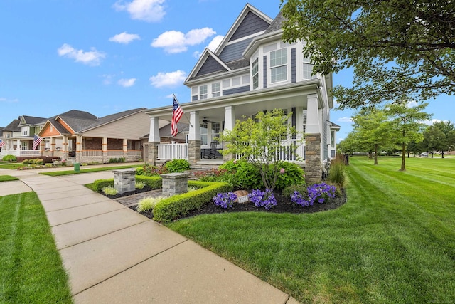 view of front of home featuring stone siding, covered porch, and a front yard