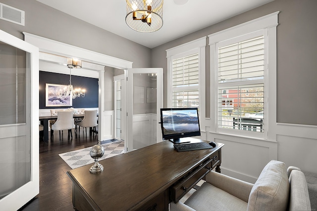 office space featuring dark wood finished floors, an inviting chandelier, visible vents, a decorative wall, and wainscoting