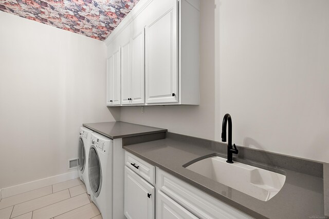 laundry room featuring cabinet space, baseboards, separate washer and dryer, and a sink