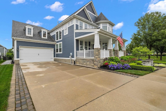 victorian-style house featuring stone siding, a shingled roof, driveway, and covered porch