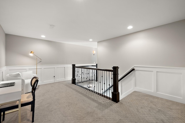interior space with a decorative wall, a wainscoted wall, and light carpet
