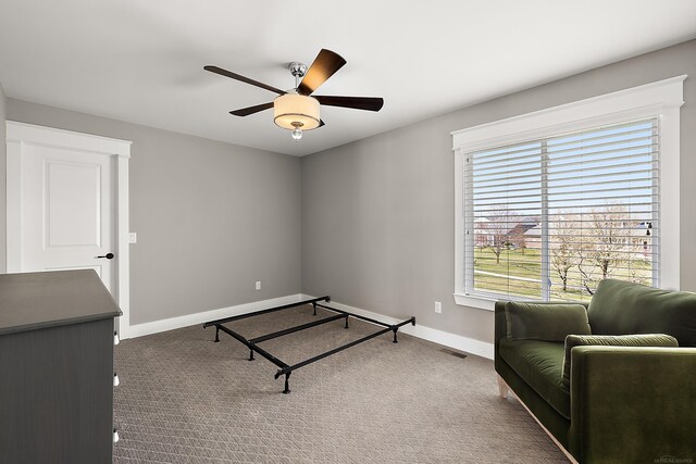living area featuring carpet floors, visible vents, baseboards, and ceiling fan
