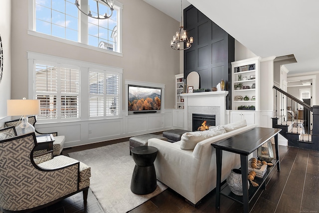 living room with plenty of natural light, dark wood-style floors, a fireplace, stairs, and a notable chandelier