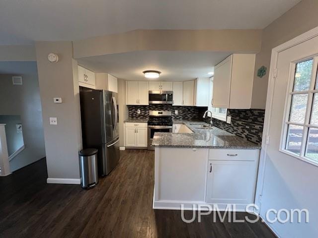 kitchen with tasteful backsplash, a sink, stainless steel appliances, white cabinets, and a peninsula
