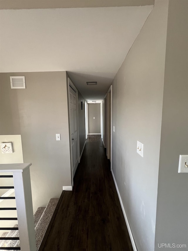 hall featuring baseboards, dark wood-style flooring, and visible vents