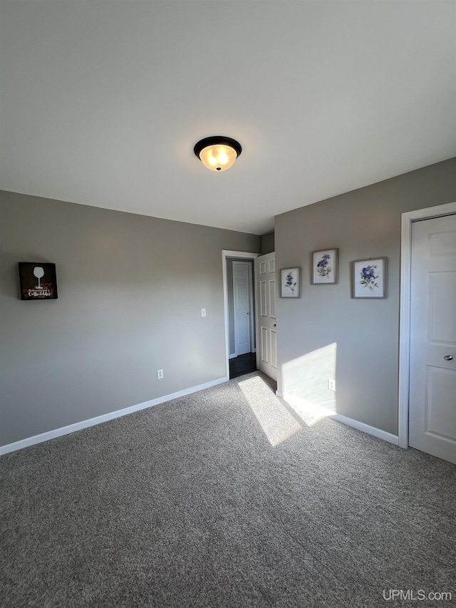 empty room featuring baseboards and carpet