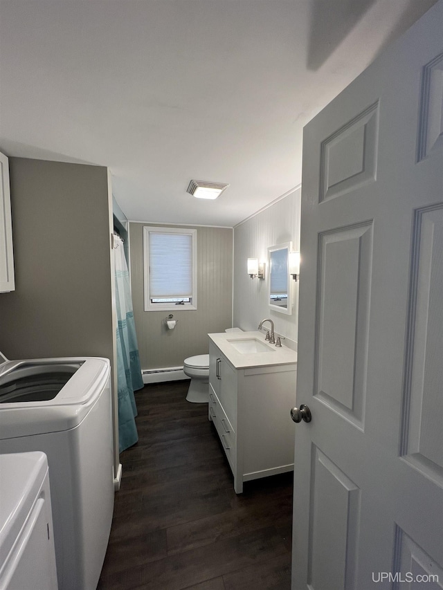 bathroom featuring a baseboard radiator, wood finished floors, vanity, washer and dryer, and toilet
