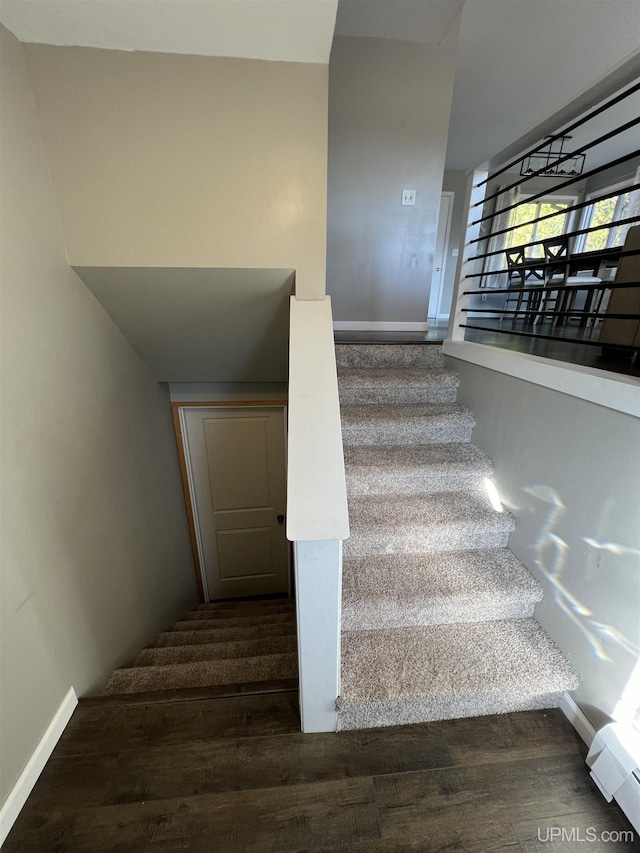 stairs with wood finished floors, baseboards, and baseboard heating