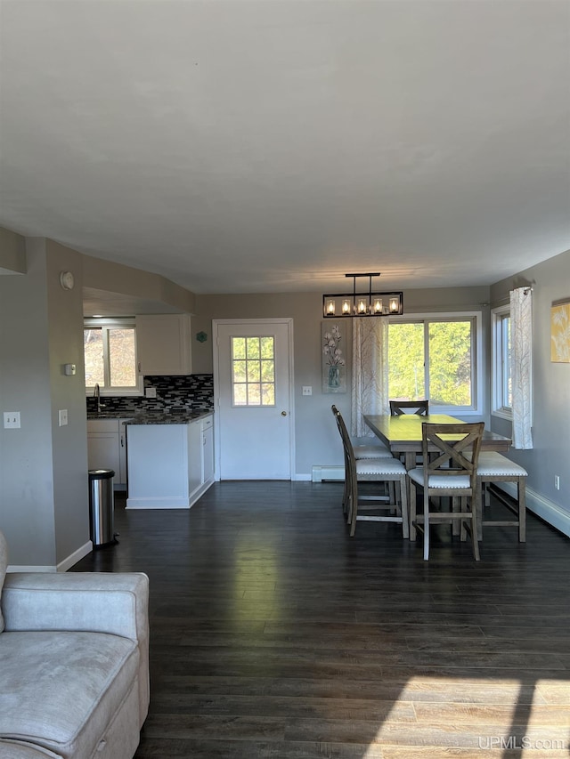 dining room with a chandelier, baseboards, dark wood-type flooring, and a baseboard radiator